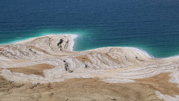 Aerial view of the unique salt formations and turquoise waters of the Dead Sea coastline.