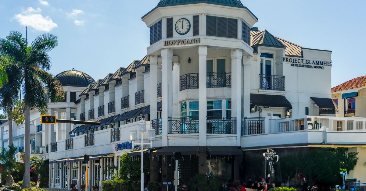 Elegant architecture at a shopping center in Naples, Florida with palm trees and clear skies.