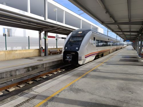 Free Passenger train at a sunny El Puerto de Santa María station, showcasing modern design and infrastructure. Stock Photo