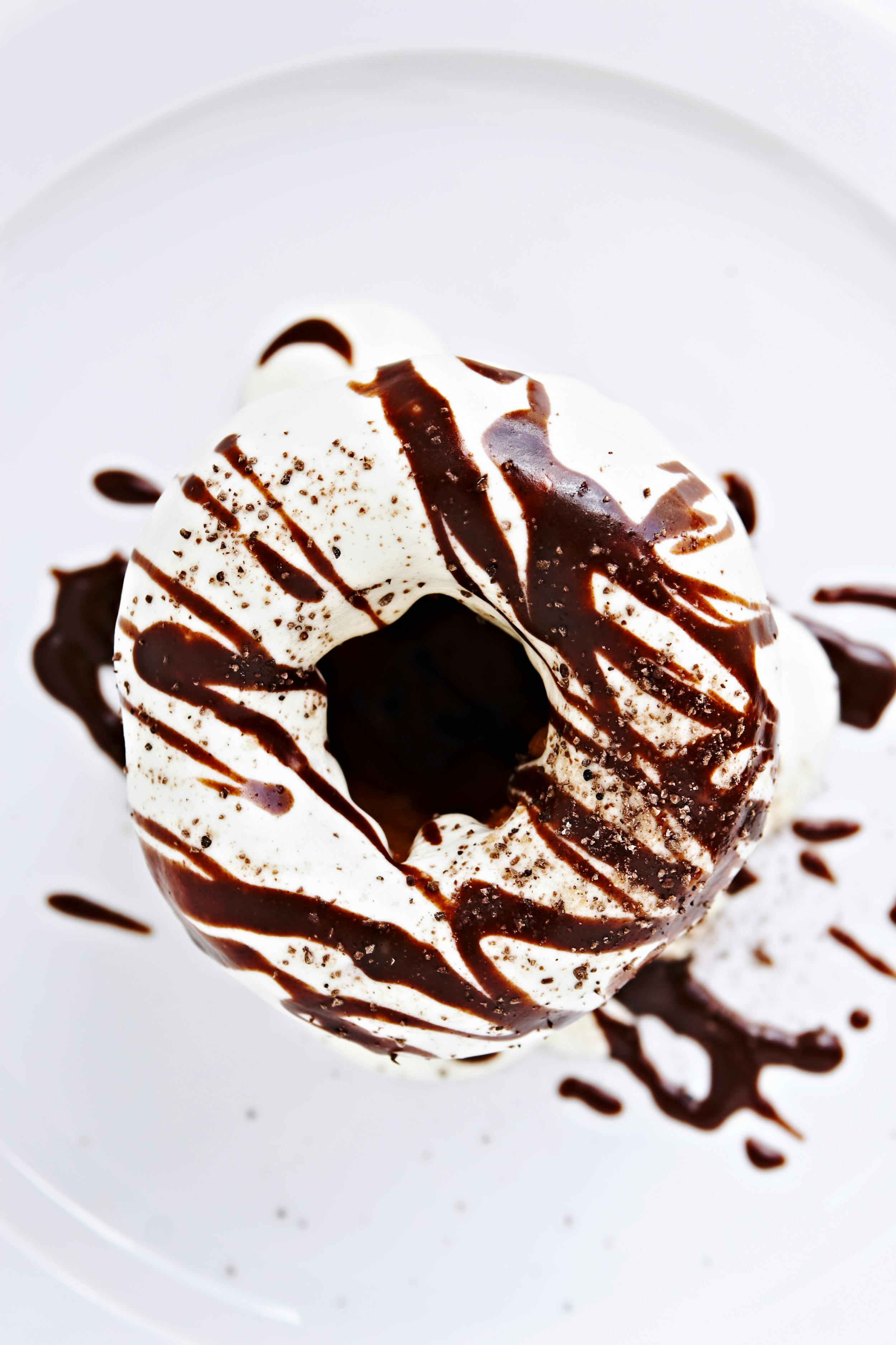 Top view of a chocolate-drizzled donut with cream, perfect for indulgent treats.