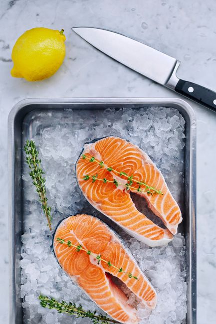 Thick pale pink wahoo fish steaks arranged on crushed ice, showing the fish's lean, fine-grained flesh.