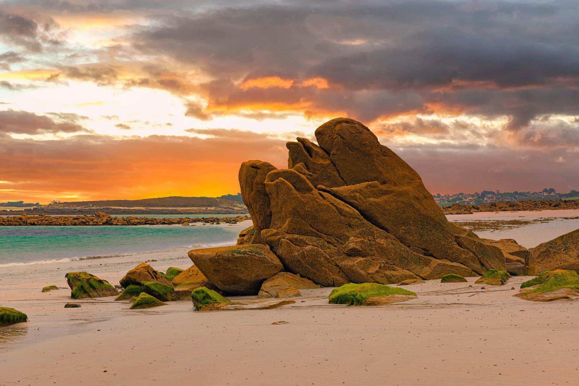 Golden hour at a serene beach with captivating rock formation and vibrant sunset colors.