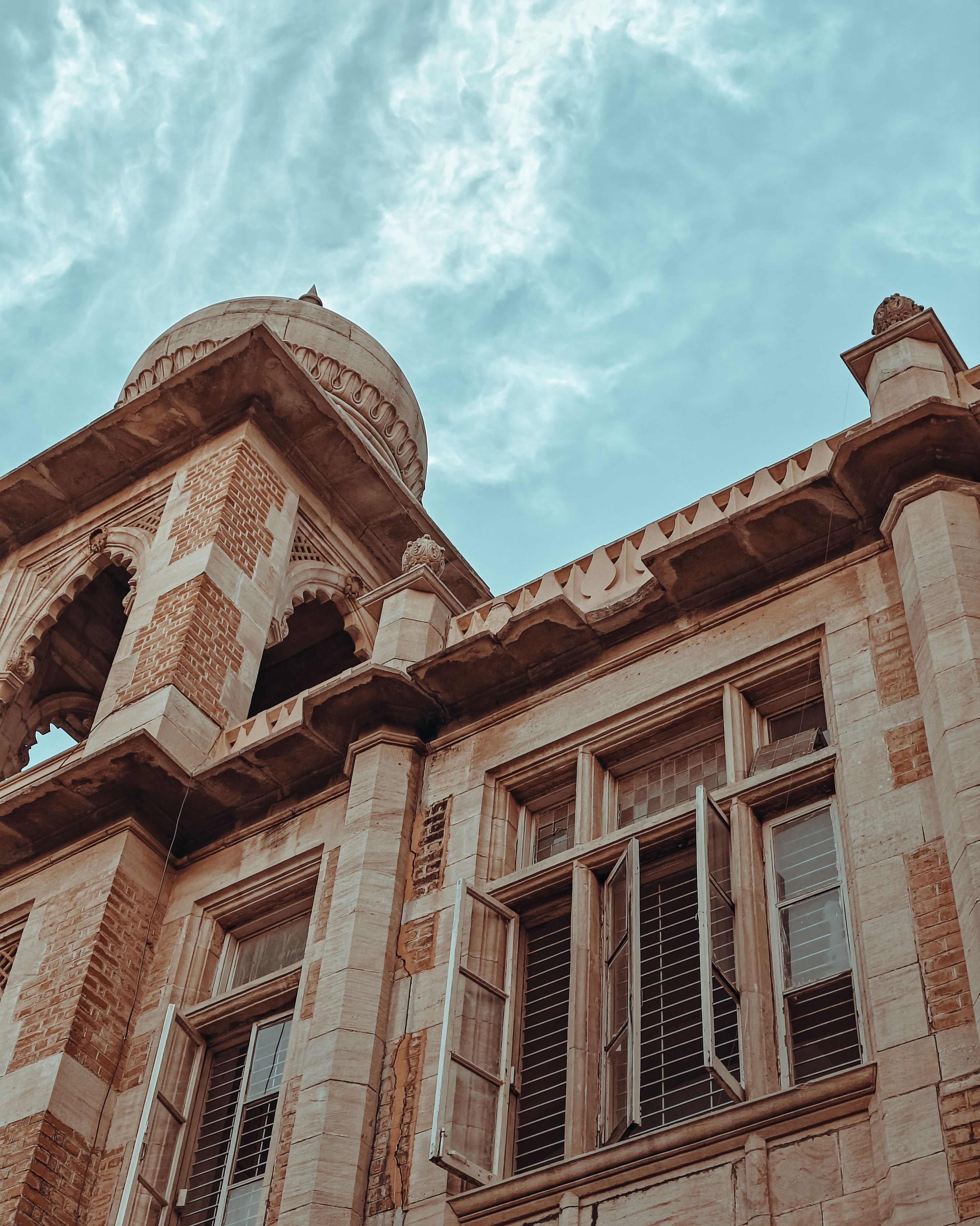 Stone building with detailed carvings, an iconic dome in India under a bright sky.