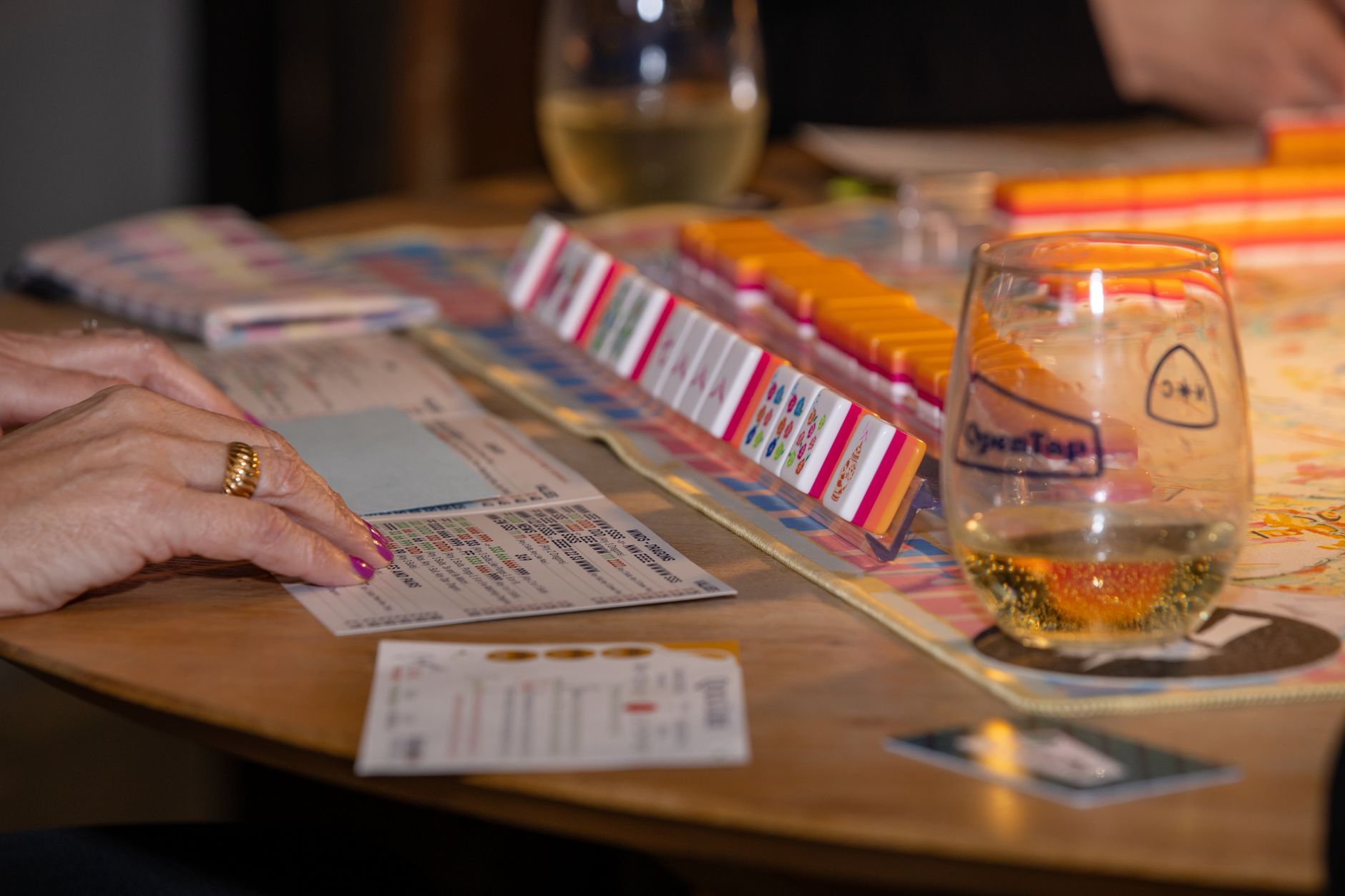 Engaging game night scene with friends playing mahjong and enjoying drinks. Perfect social moment.