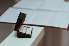 A pair of wedding rings in a black box next to important documents, symbolizing commitment.