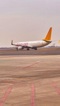 A commercial airplane taxis on an airport runway under a cloudy sky, preparing for takeoff.