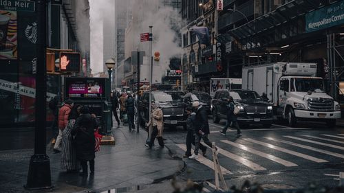 Free Urban scene in downtown Manhattan showing people and traffic under atmospheric cloudy skies. Stock Photo