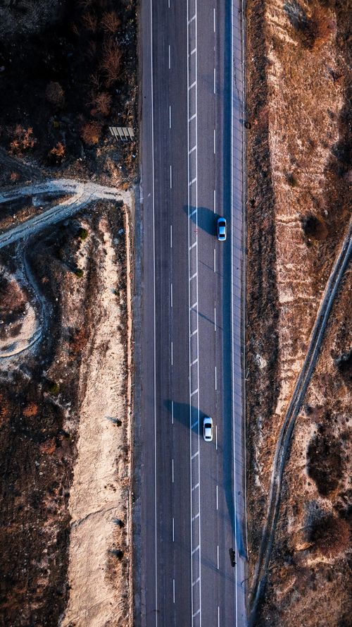 Free Dramatic aerial shot of two cars on a remote desert highway, showcasing vast landscapes. Stock Photo