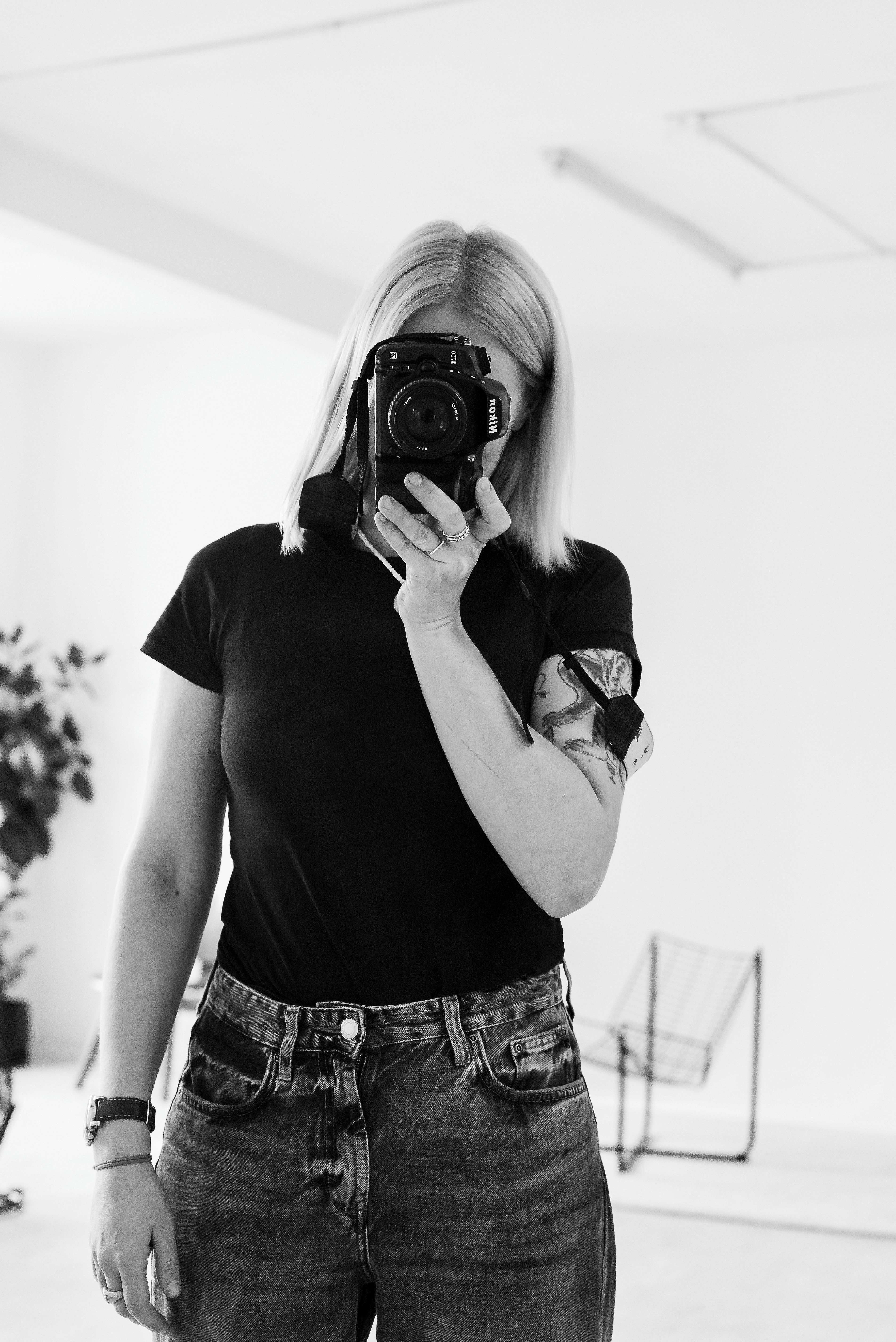 Monochrome portrait of a woman taking a selfie with a camera.