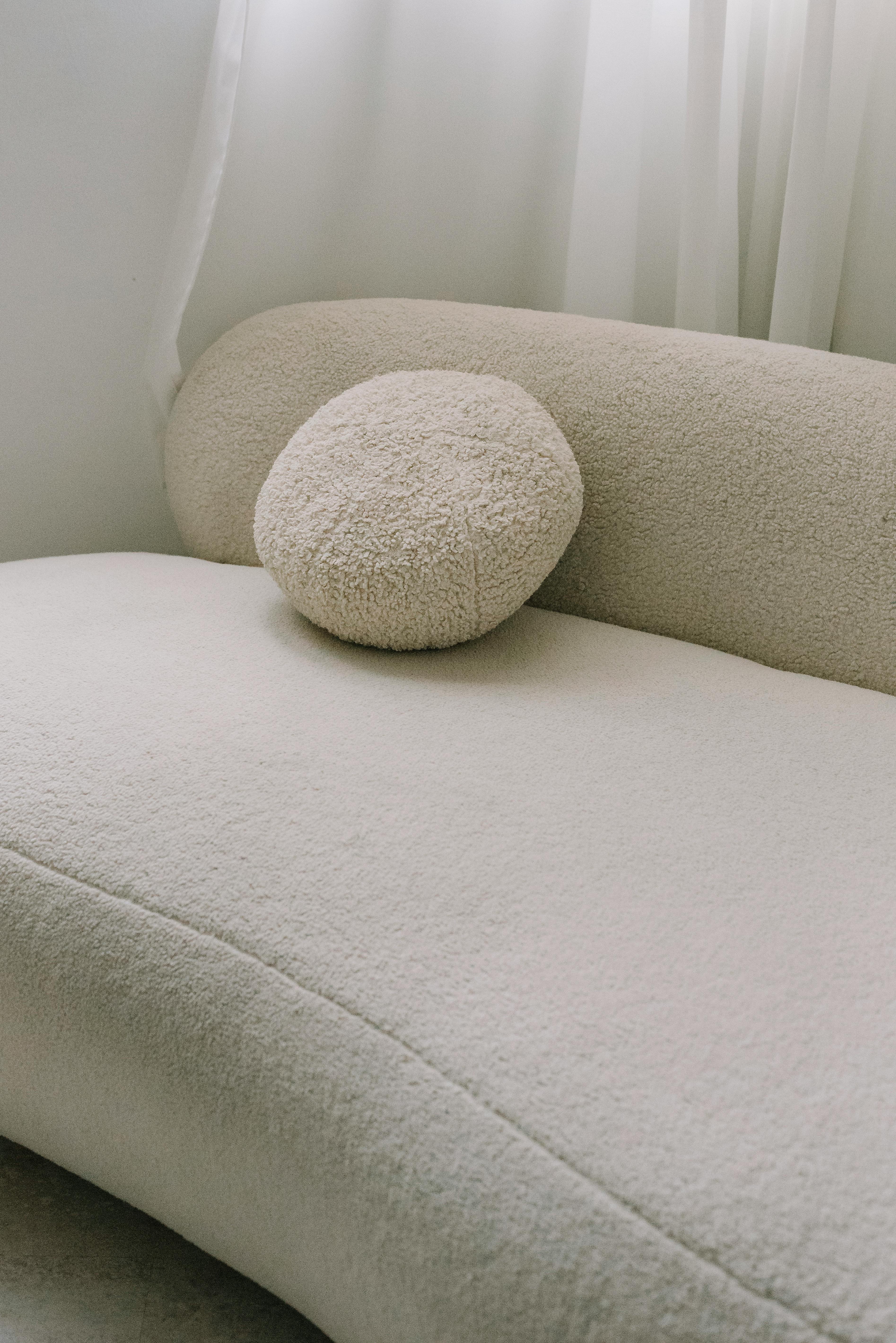 Stylish cream sofa with a round cushion, perfect for modern living spaces.