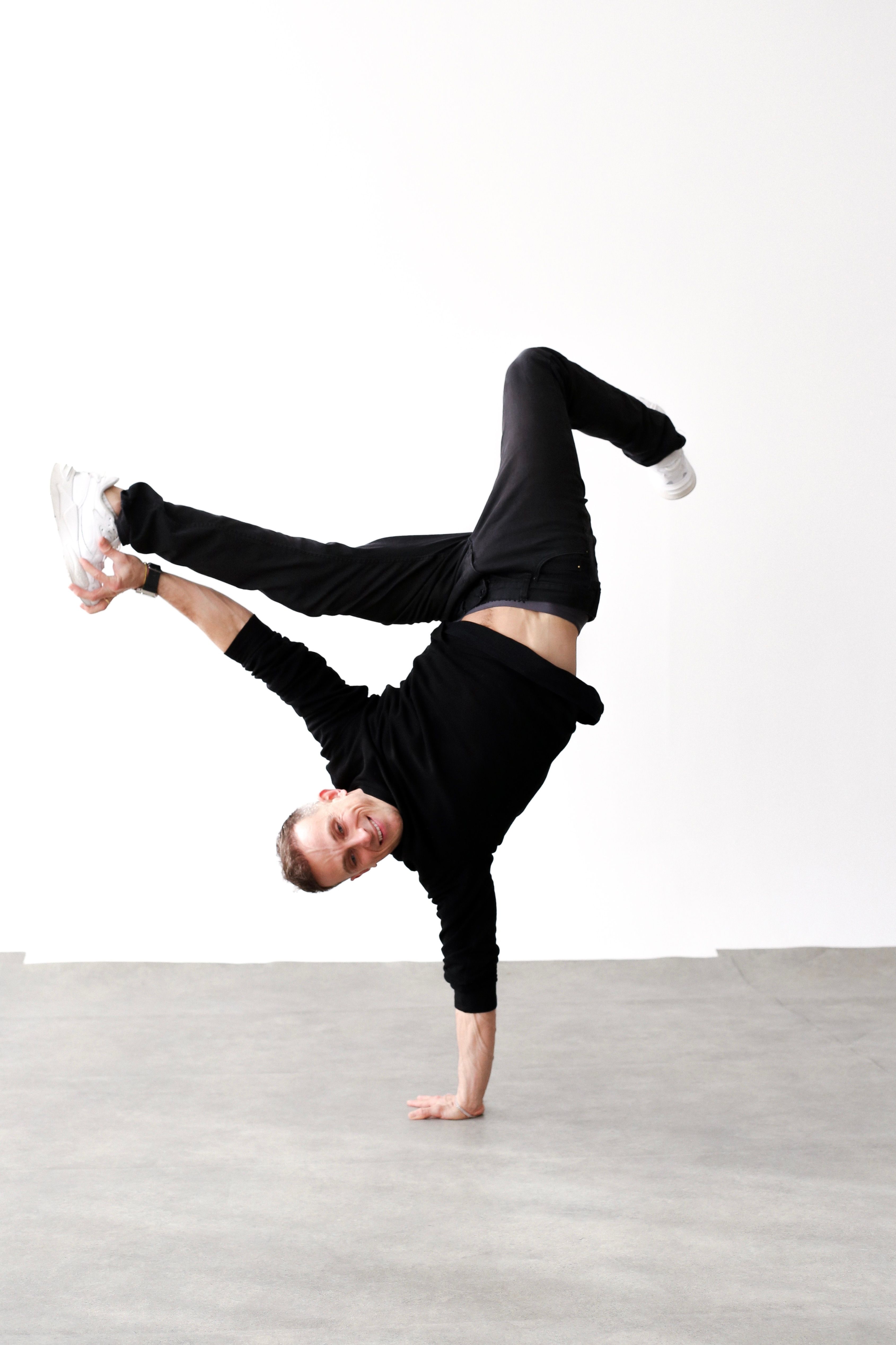 A skilled breakdancer executing a handstand move in an urban setting in Berlin.