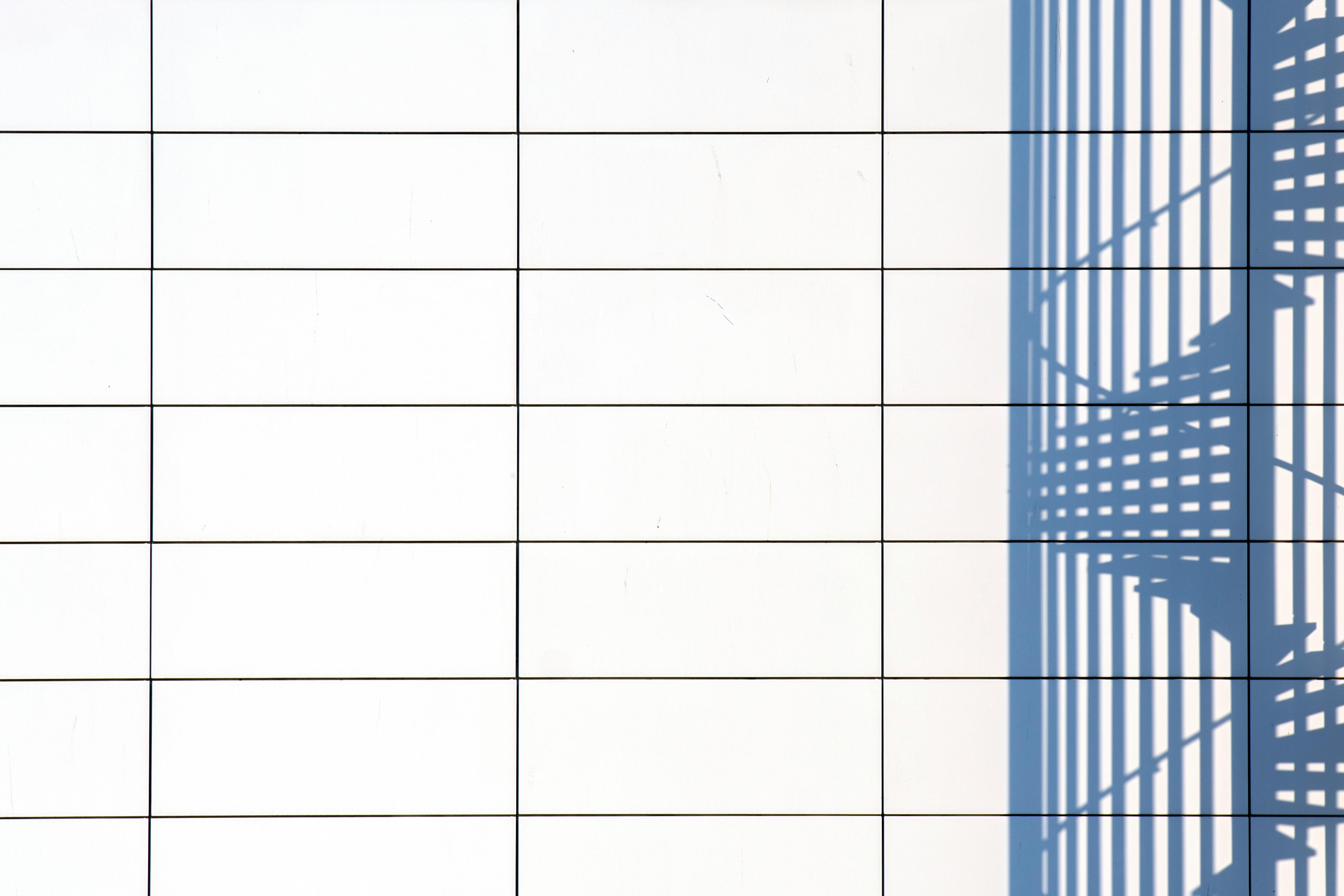 bezplatná Minimalistický obraz vrhání stínů na bílou kachlovou stěnu, ideální pro použití v moderním designu. Základová fotografie