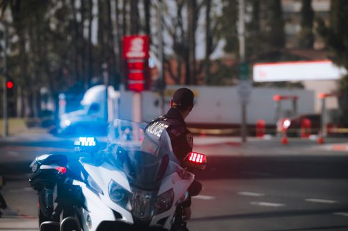Free Police officer on motorcycle with flashing lights on city street during daytime. Stock Photo