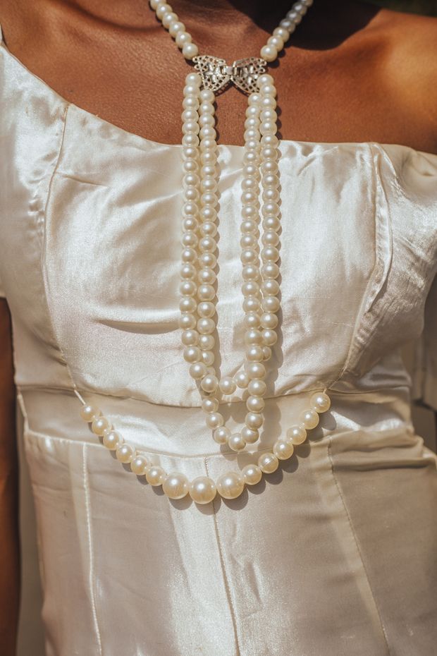 Pearl necklace resting on white silk — photo by Amina Bawa on Pexels