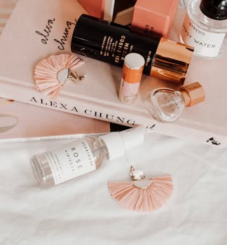 Chic flat lay featuring beauty products and jewelry atop an Alexa Chung book, conveying elegance and style.