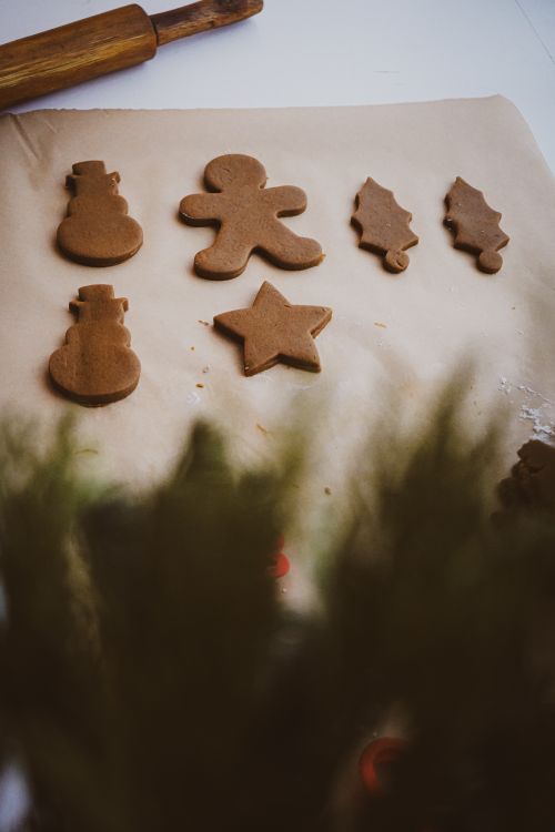 Free Christmas-themed gingerbread cookies prepared on parchment paper, ready for baking. Stock Photo