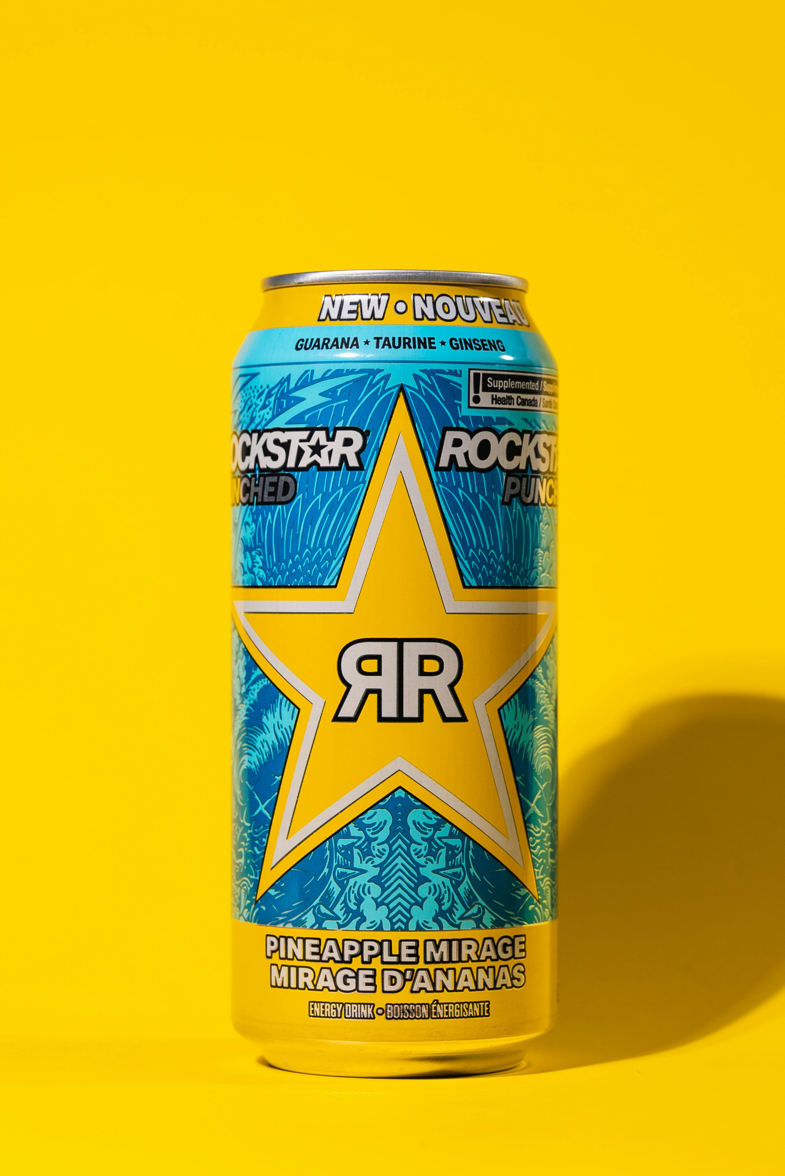 Colorful Rockstar Energy Drink can with pineapple flavor on a vivid yellow background.