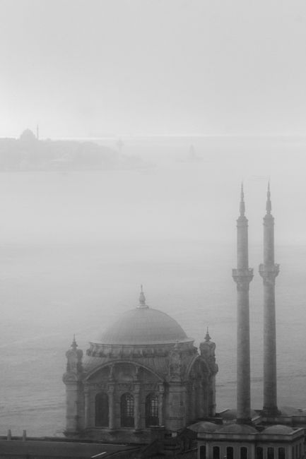 Black and white photo of Istanbul mosque shrouded in fog by the Bosphorus Strait.
