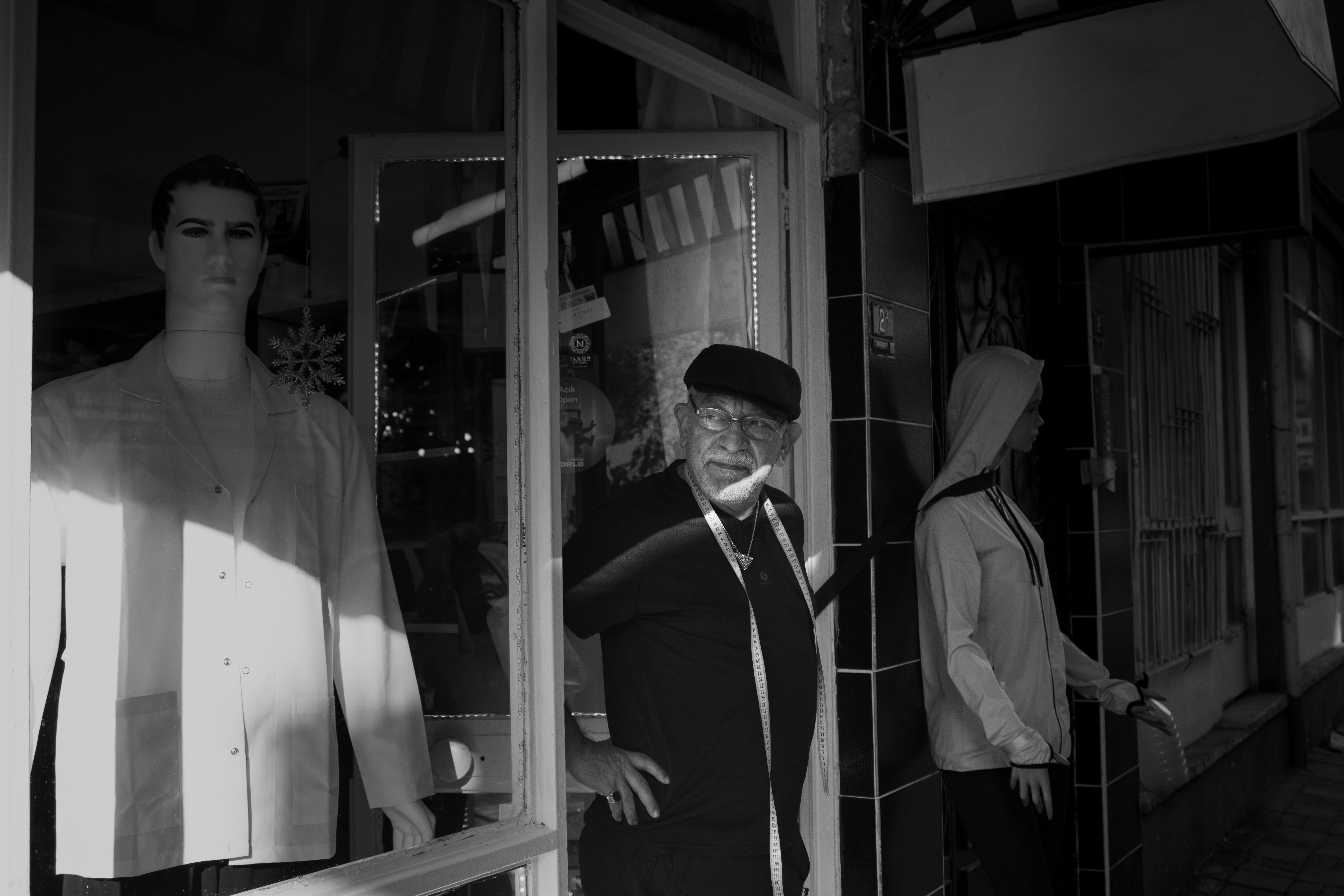 Monochrome image of a tailor with mannequins in a classic shop setting.