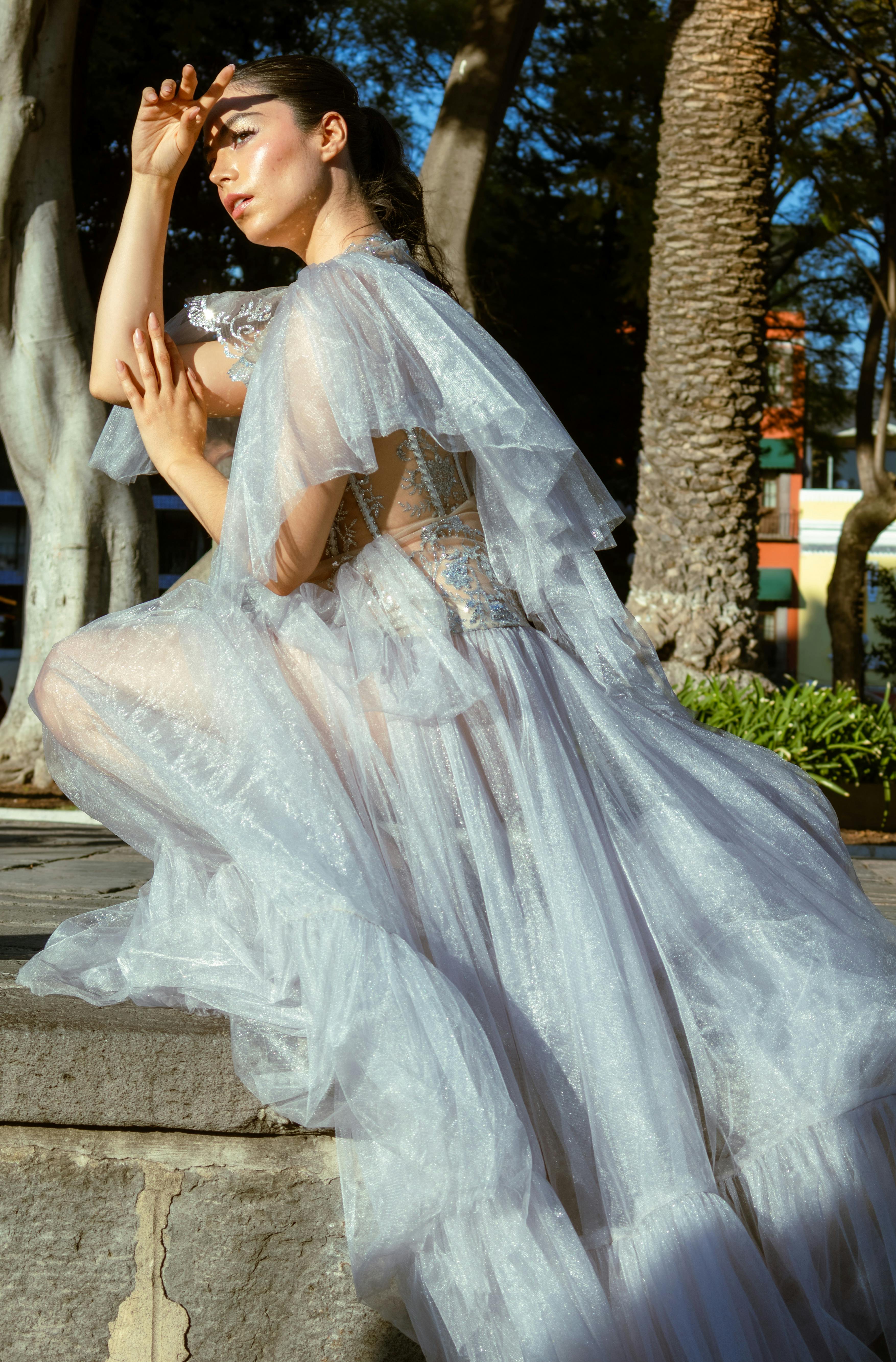 Graceful woman in a white gown poses in sunlight, Puebla, Mexico.