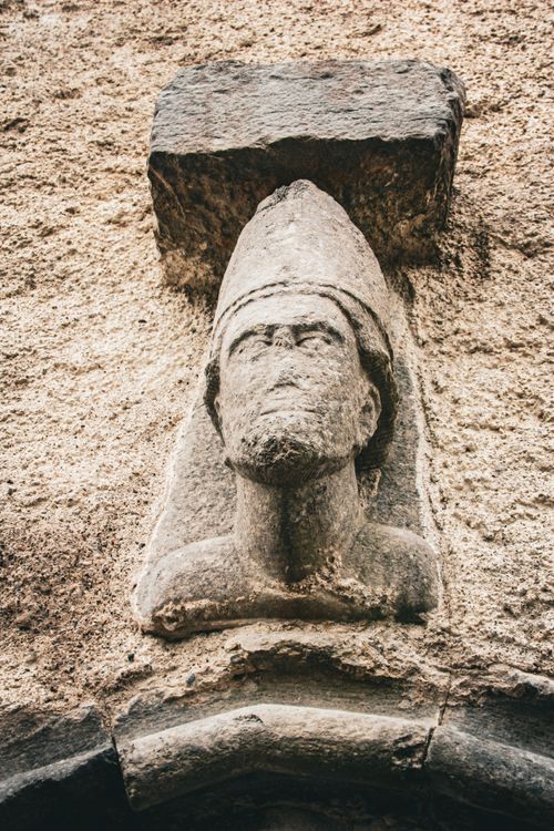 Free A detailed stone statue on an ancient weathered wall, showcasing historical craftsmanship. Stock Photo