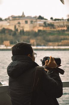 Man with camera photographs historic landscape from a riverside.