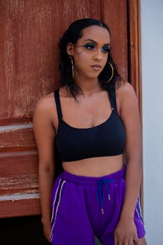 一位穿着运动服的时尚年轻女性在小门旁摆姿势