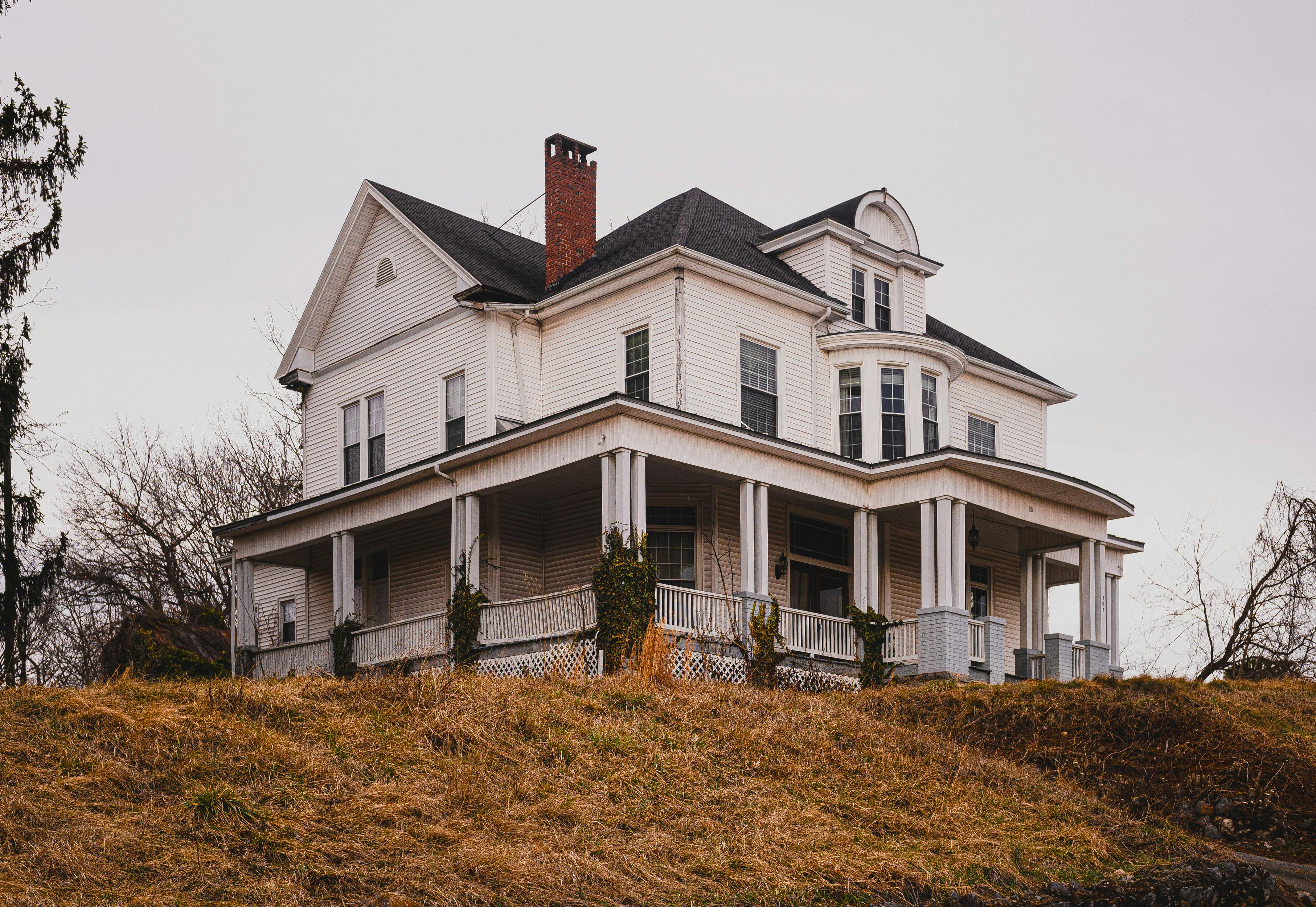 Beautiful historic white house with a wraparound porch set against autumn surroundings.