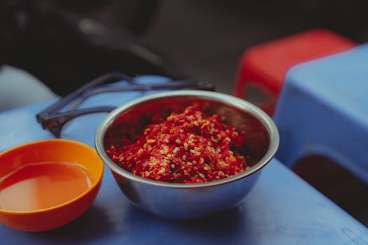 A close-up of chopped red chili peppers in a metal bowl on a blue table in Ho Chi Minh City.