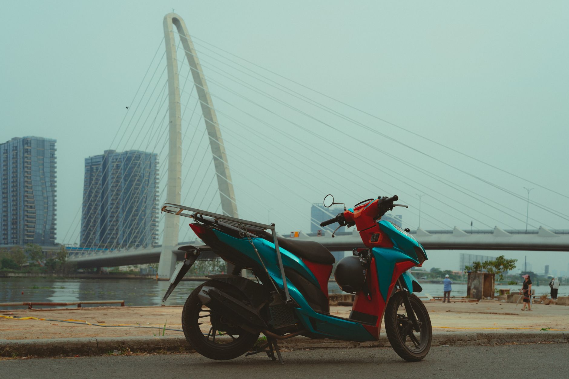 Motorcycle parked near an iconic bridge in Ho Chi Minh City, Vietnam.