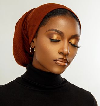 Beautiful close-up portrait of a woman with golden makeup and headscarf.