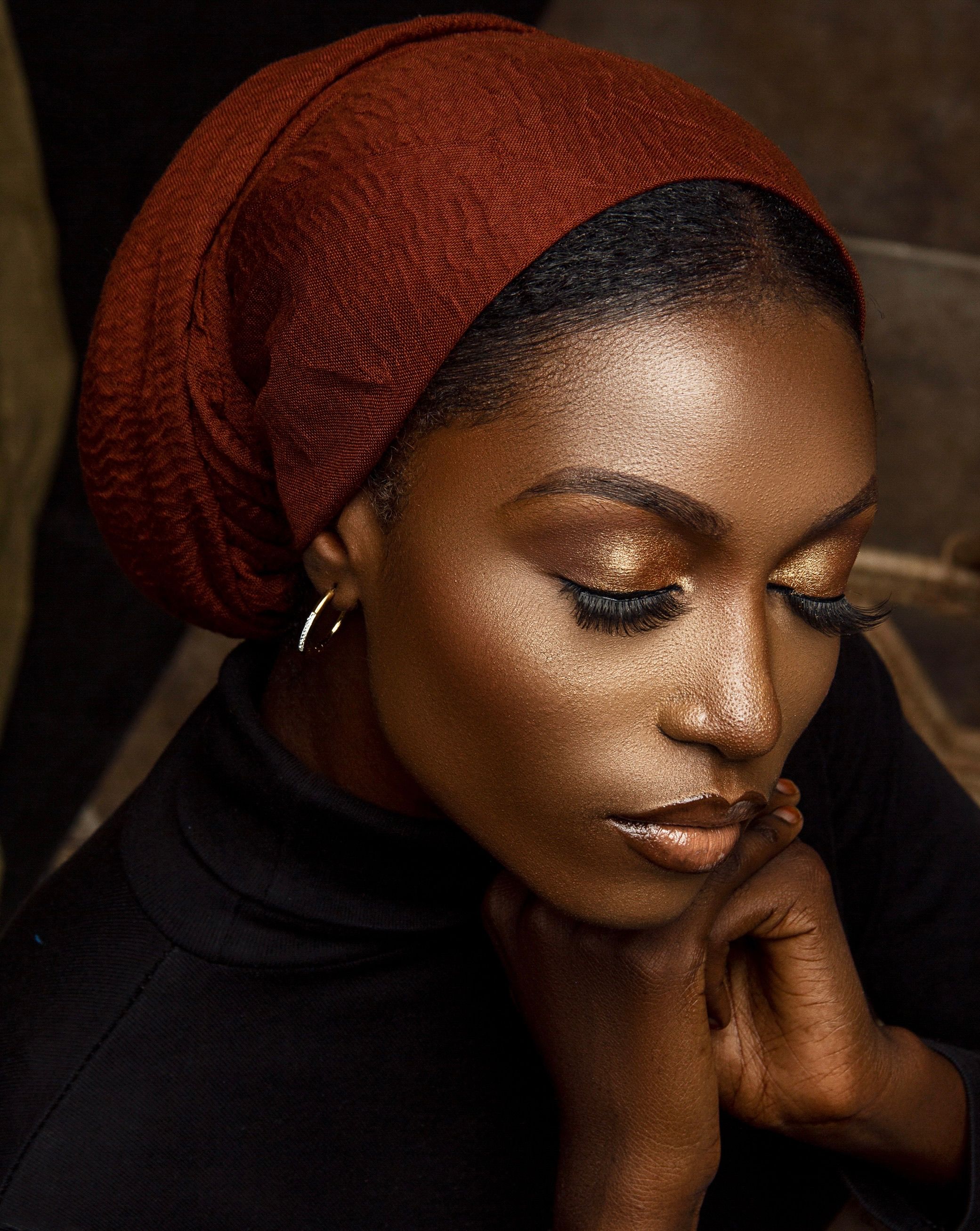Close-up portrait of a woman with elegant makeup and a brown headscarf.