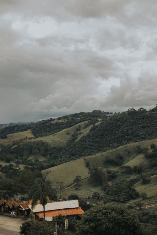 Free Scenic view of lush green hills under a cloudy sky, evoking tranquility. Stock Photo