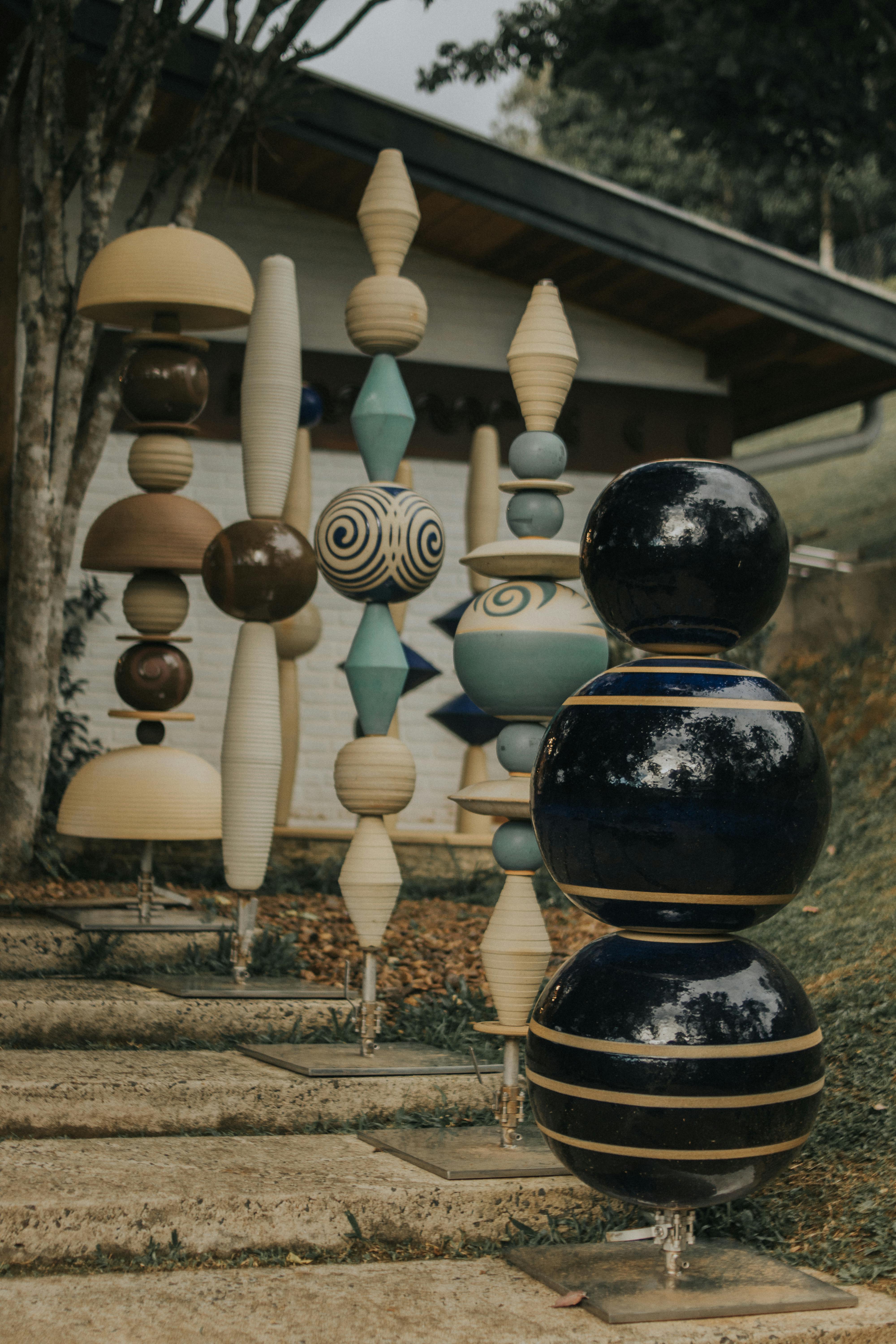 Vibrant ceramic sculptures displayed outdoors next to a modern house.
