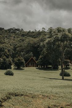 A serene cabin nestled in a green forest clearing under cloudy skies.