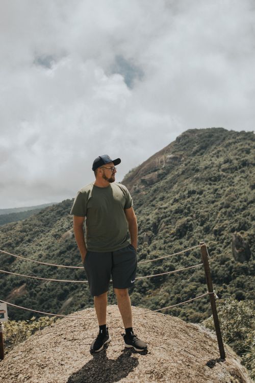 Free Man in casual clothing on mountain top with a scenic view. Ideal for adventure themes. Stock Photo