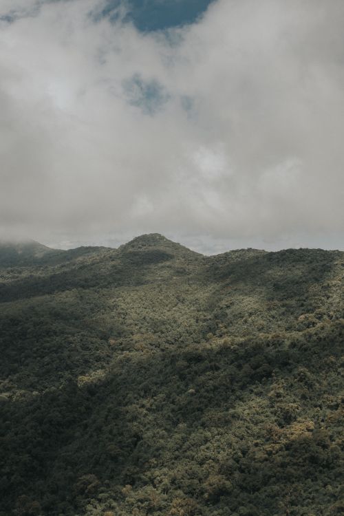Free Lush green mountain landscape beneath a cloudy sky, evoking tranquility in nature. Stock Photo