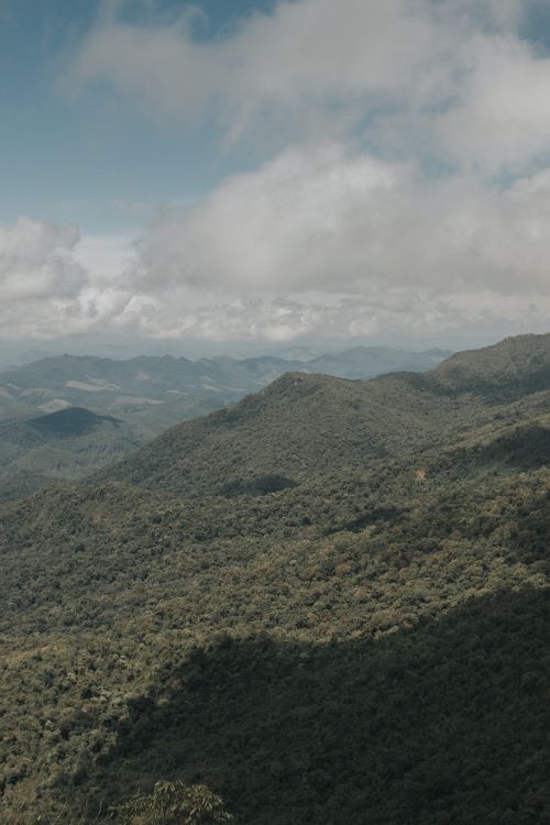 Free A stunning aerial shot of vast green mountain ranges beneath a cloudy sky. Stock Photo