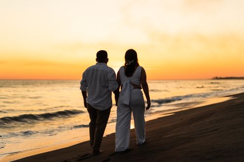 Free A couple walks hand in hand along the beach at sunset, capturing a romantic moment. Stock Photo