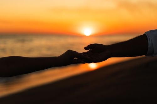 Free A couple holding hands during a romantic beach sunset, capturing a moment of love and connection. Stock Photo