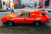 一辆经典的红色旅行车停在城市街道上，尽显复古风格