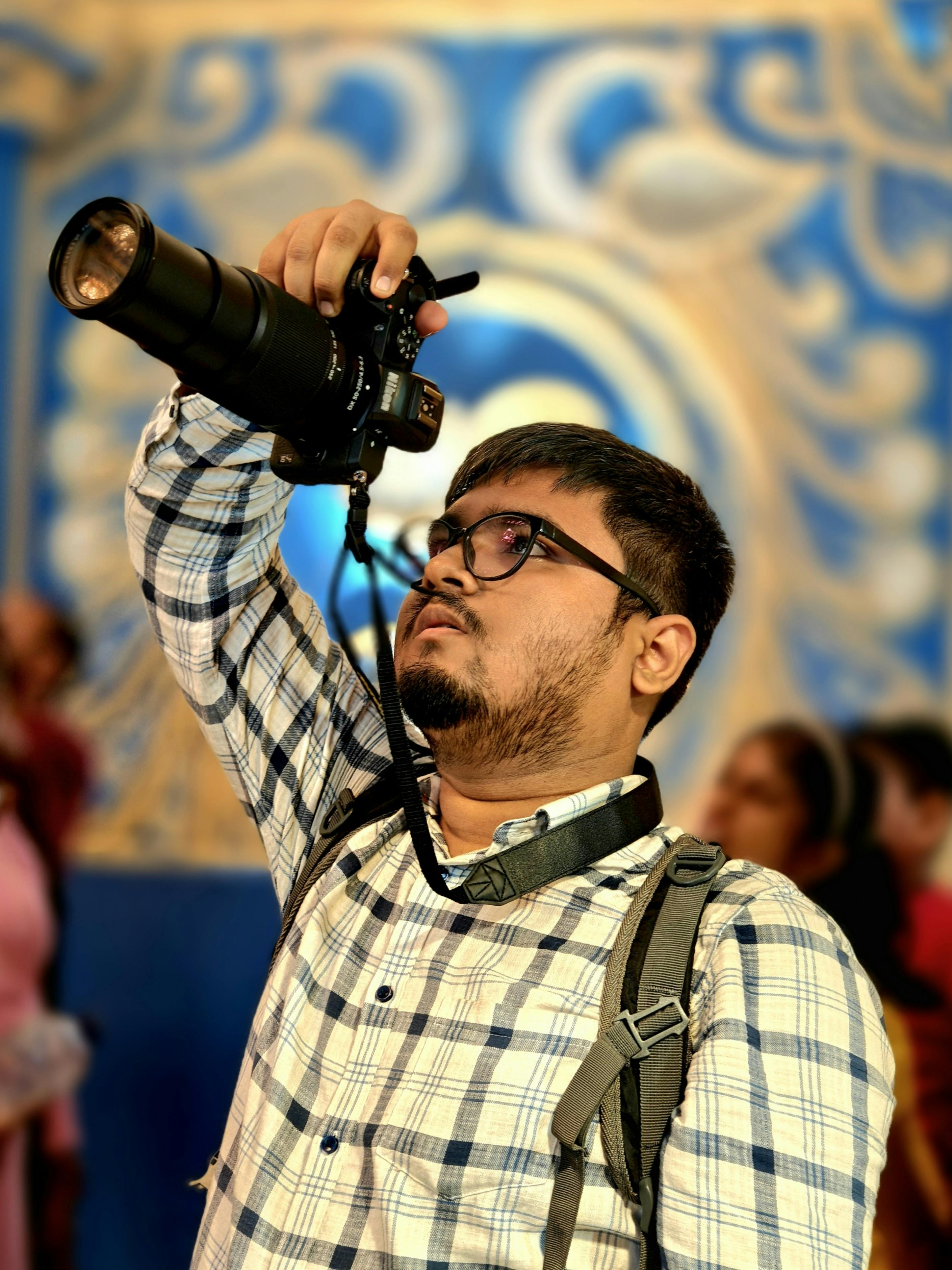Young photographer taking pictures indoors in Howrah, India.