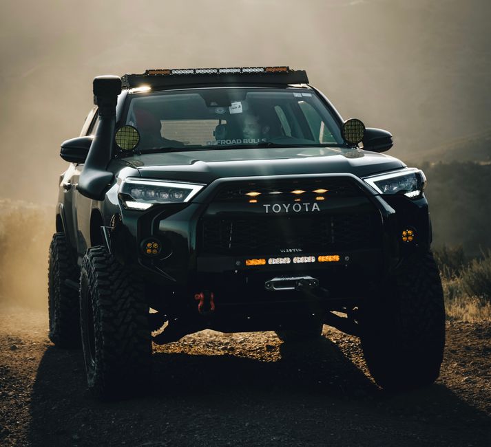 Powerful Toyota truck navigating rugged terrain in dusty conditions.