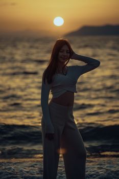 A silhouette of a young woman posing by the sea during a beautiful sunset.