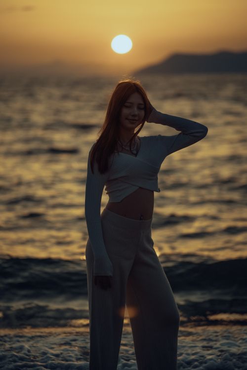 Free A silhouette of a young woman posing by the sea during a beautiful sunset. Stock Photo