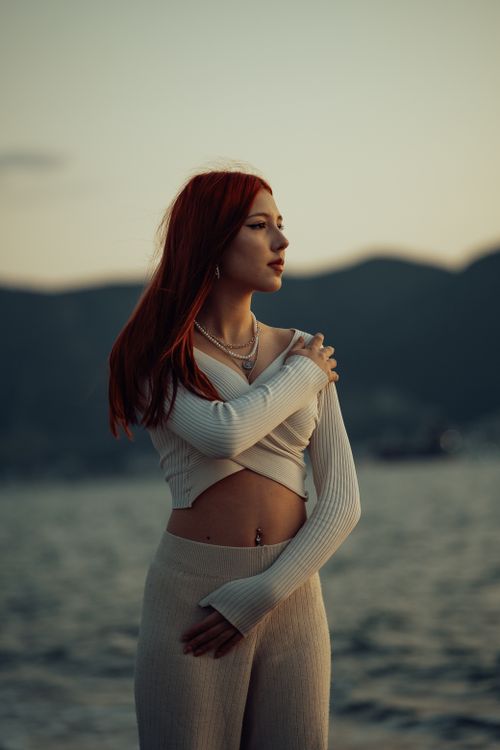 Free A contemplative woman stands by the sea at twilight, embracing tranquility. Stock Photo