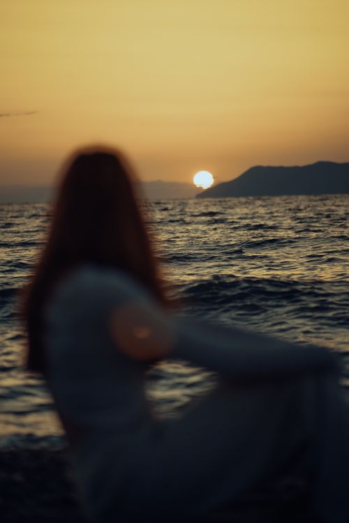 Free Serene scene of a silhouette viewing a warm, vibrant ocean sunset. Stock Photo