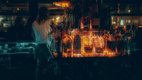 Free Warm, moody bar interior with glowing liquor bottles creating an intimate atmosphere. Stock Photo