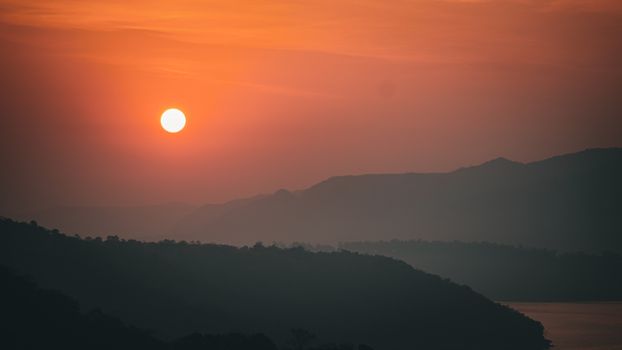 Mesmerizing sunset over Mulshi Lake with silhouetted hills, capturing nature's tranquil beauty.