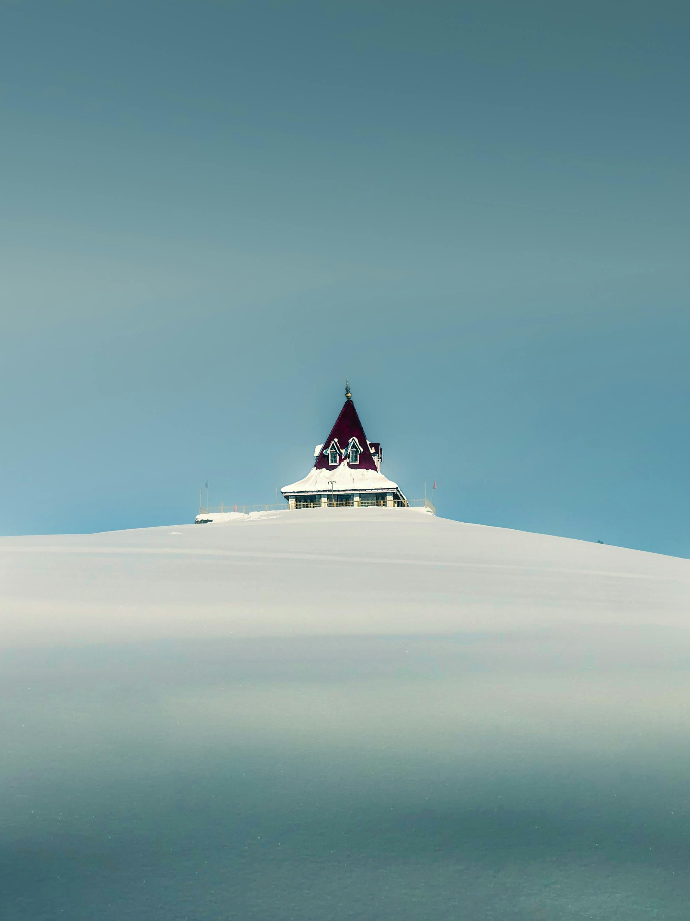 Lonely building on a snow-covered hill against a clear winter sky.